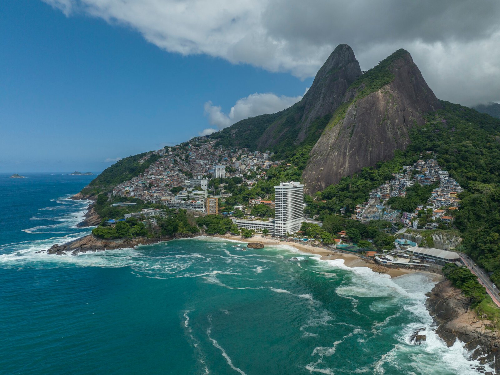 Vista panorâmica do Morro Dois Irmãos, no Leblon, Rio de Janeiro, com o mar e a cidade ao fundo.